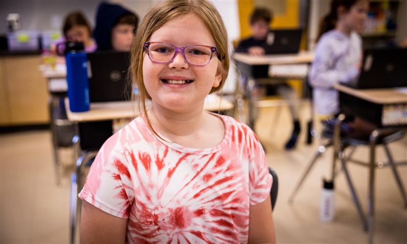 A girl wearing a pink shirt smiles